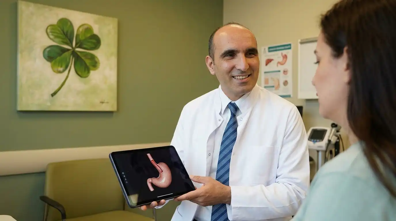 A male bariatric surgeon in a white coat showing a stomach model on a tablet to a patient in a green clinic with a four-leaf clover painting